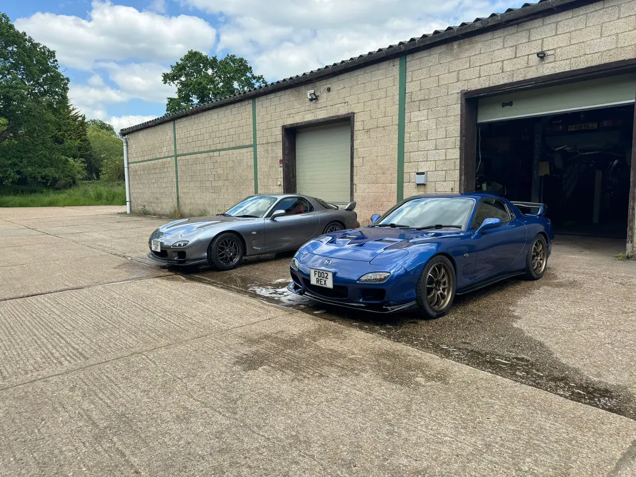 Mazda RX-7s parked outside the workshop