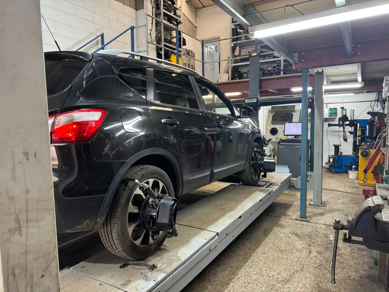 Car on the alignment ramp with a wheel removed for suspension work